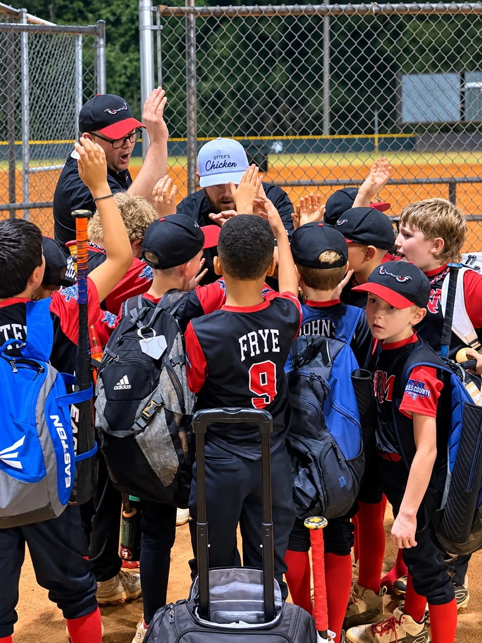 Oregon Park 9U baseball team celebrating a playoff win with their coach wearing an Otter’s Chicken hat.